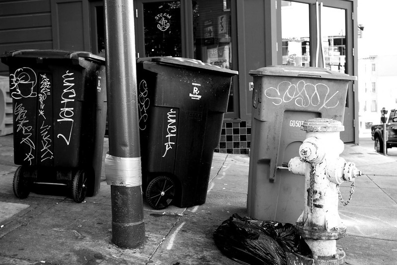 Sidewalk, with three trash bins.